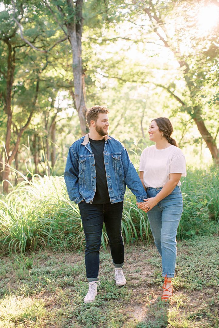 stylish couple holding hands and walking for engagement photos at McKinney Falls
