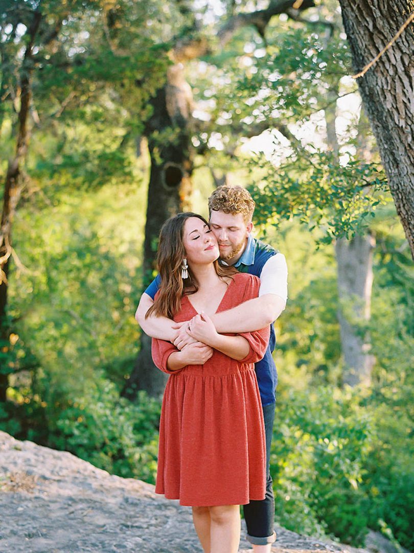 girl in red dress hugging her fiance at McKinney Falls State Park