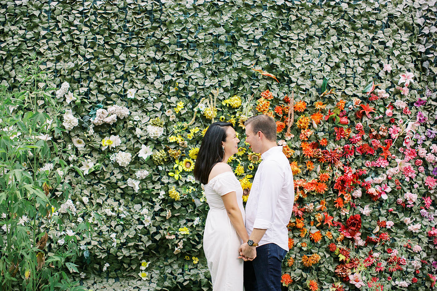 engaged couple posing in front of a floral wall at Sekrit Theatre