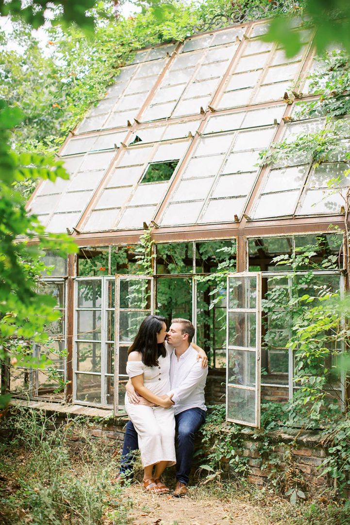engagement photo of a couple sitting outside the greenhouse at Sekrit Theatre