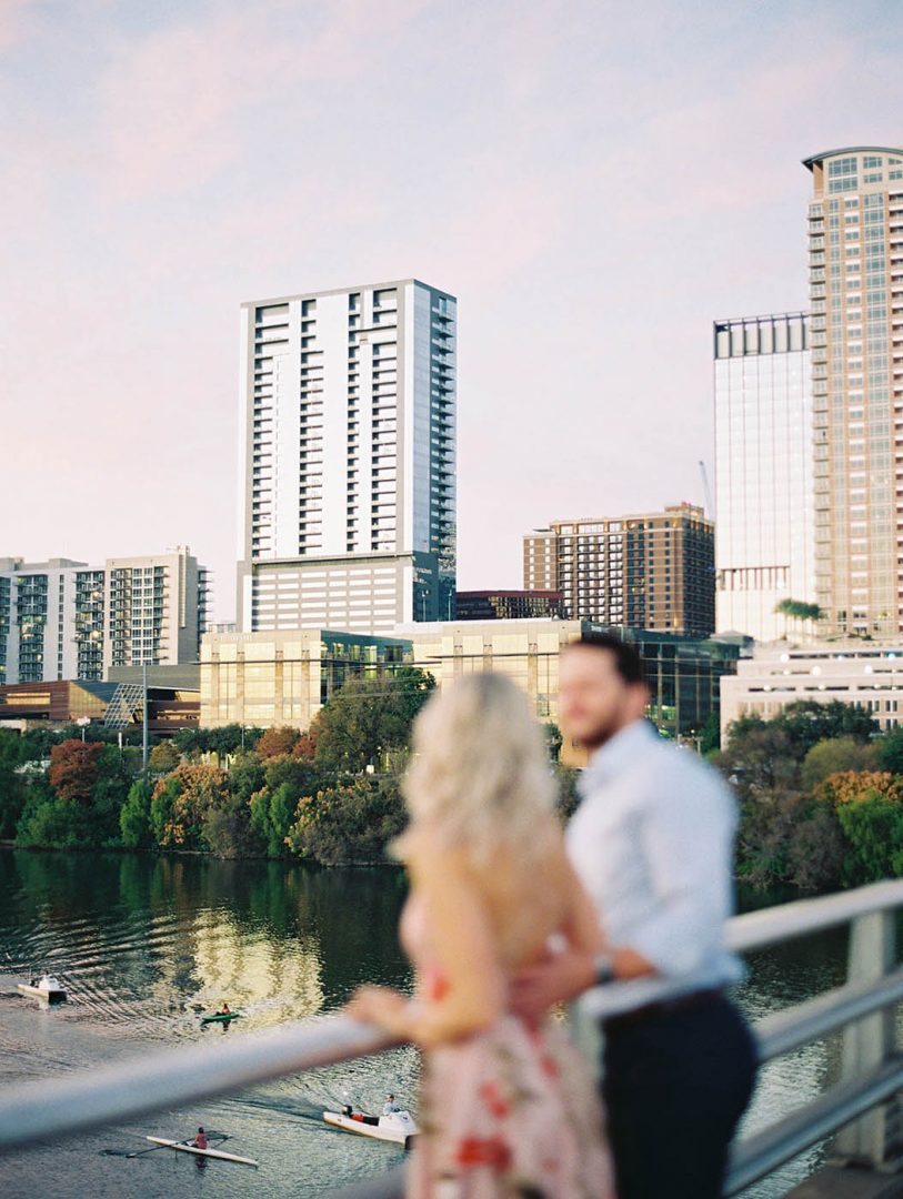 Couple looks out on Lady Bird Lake during sunset from the South Congress bridge