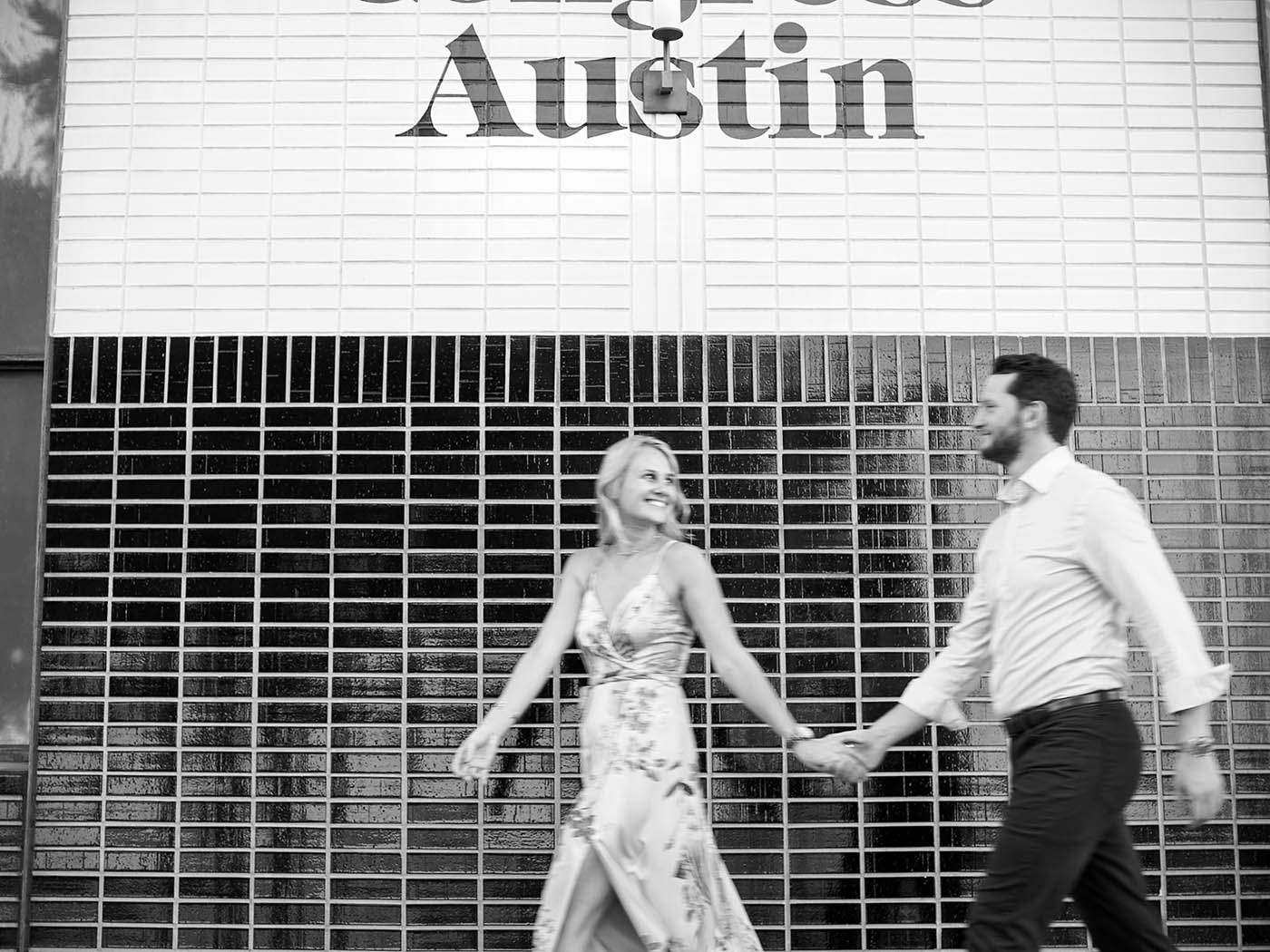 Blurry engagement photo of a couple walking past the South Congress Hotel