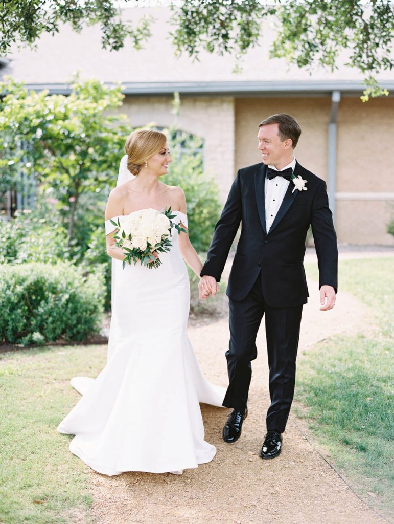 the bride and groom walk together with the bridal bouquet