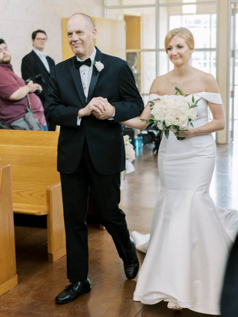 the bride is escorted down the aisle at All Saints Chapel