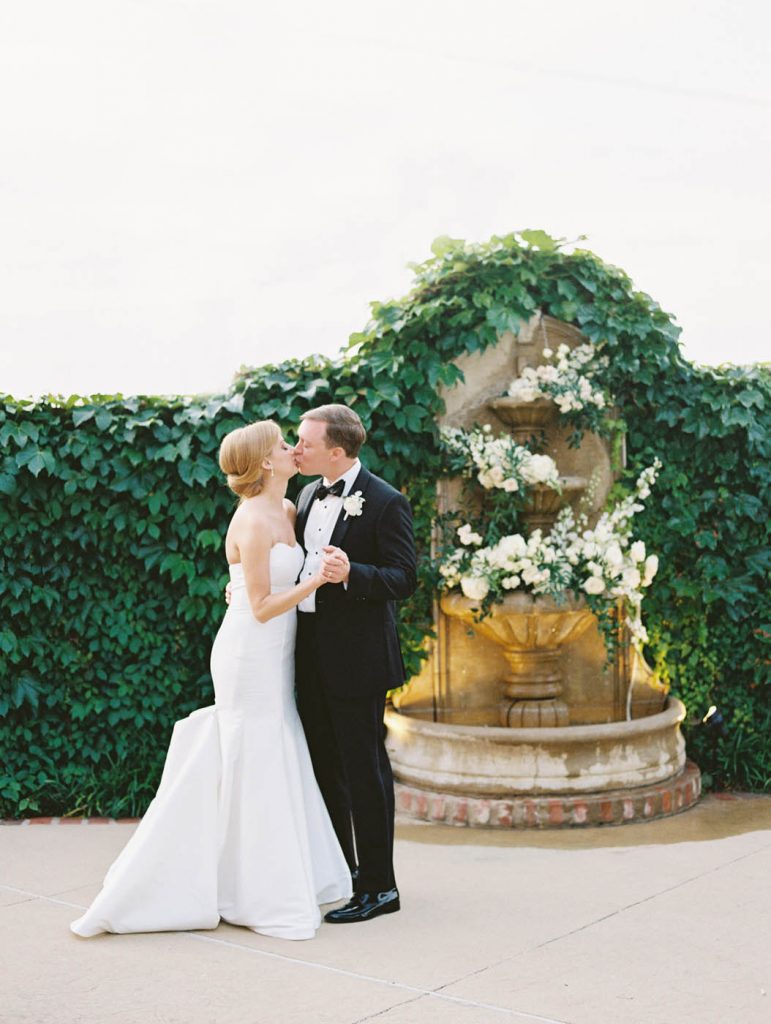 The bride and groom kiss by the fountain
