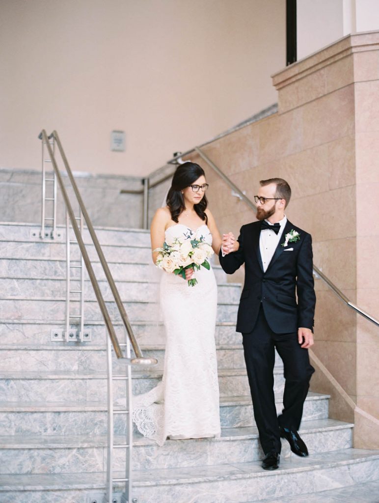 Groom leads bride down stairs of Bass Hall