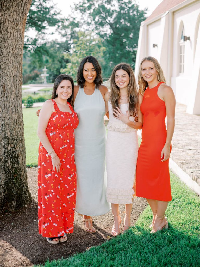 The bride shows off her ring next to friends in colorful dresses