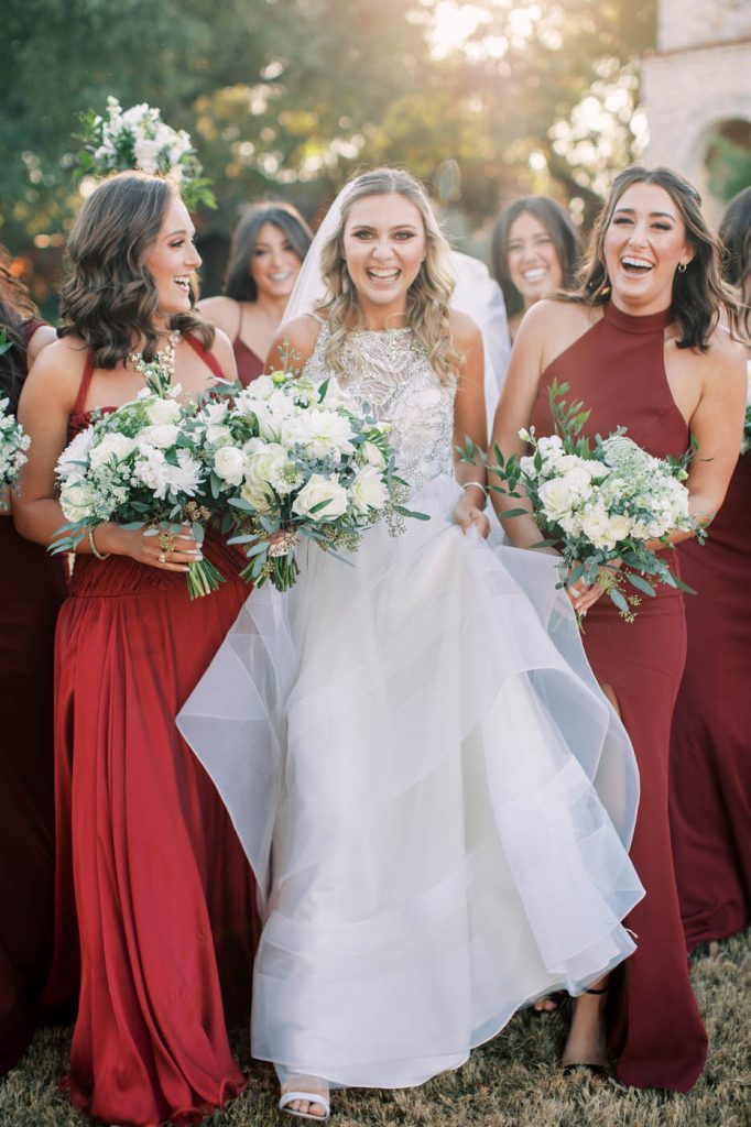 bride walking with bridesmaids in maroon dresses