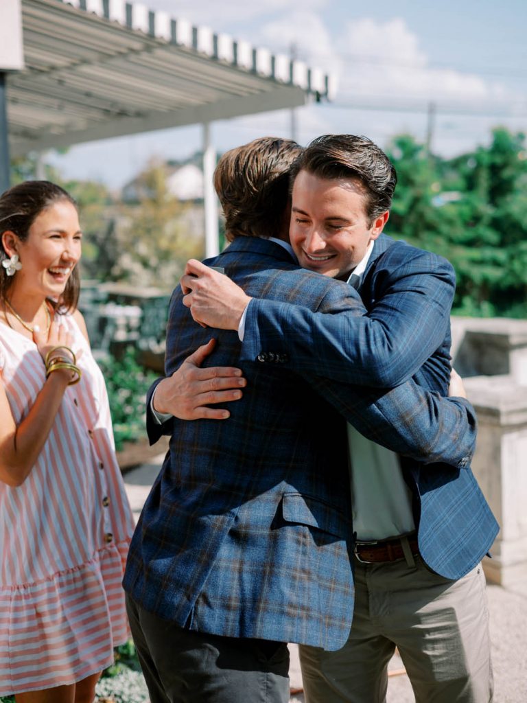 The groom hugs his family after proposing