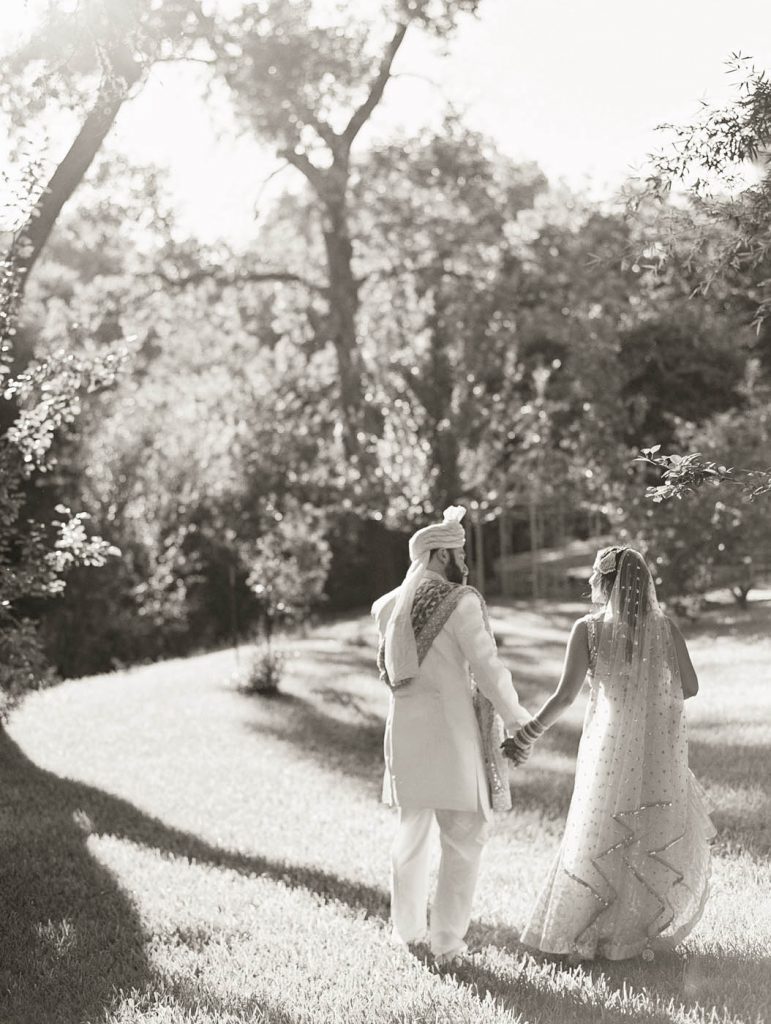 the indian bride and groom walk together at Jennifer's Gardens