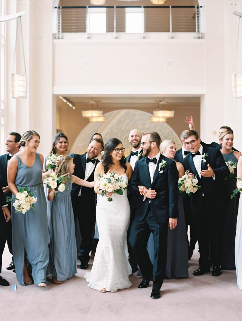 Bridesmaids in blue dresses walk with groomsmen