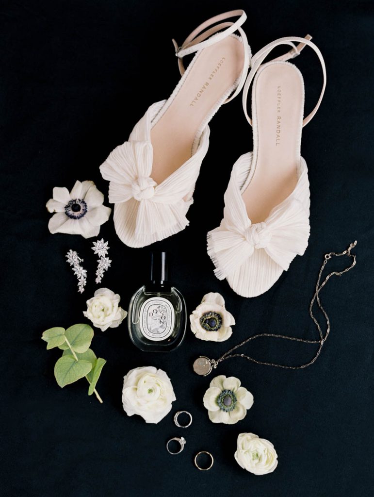 flatlay on a black background of bridal details including Loeffler Randall shoes