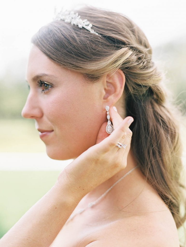 bride holding her earring wearing a tiara