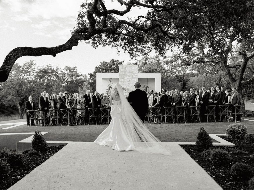 the bride walks down the aisle as the guests look back at her