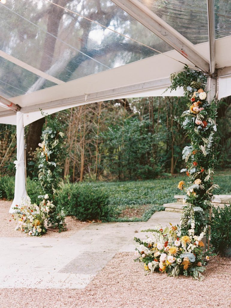 asymmetrical floral installation at an outdoor tented wedding