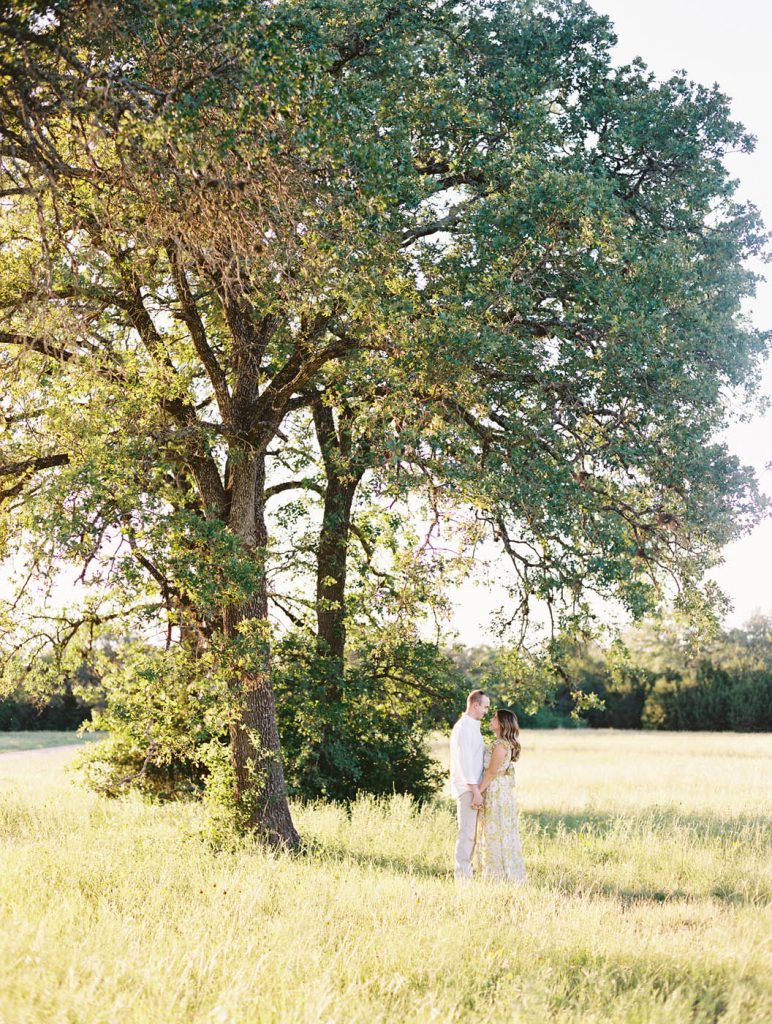 couple poses under an oak tree at circle c park in austin