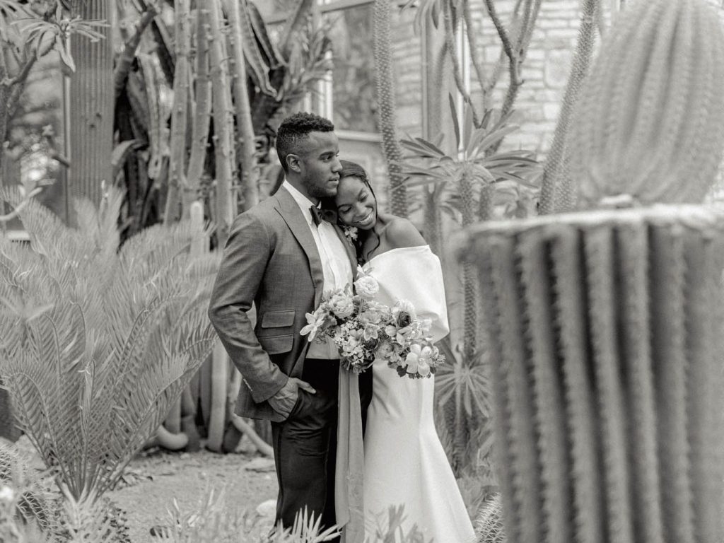 black and white photo of a couple embracing at the greenhouse at driftwood