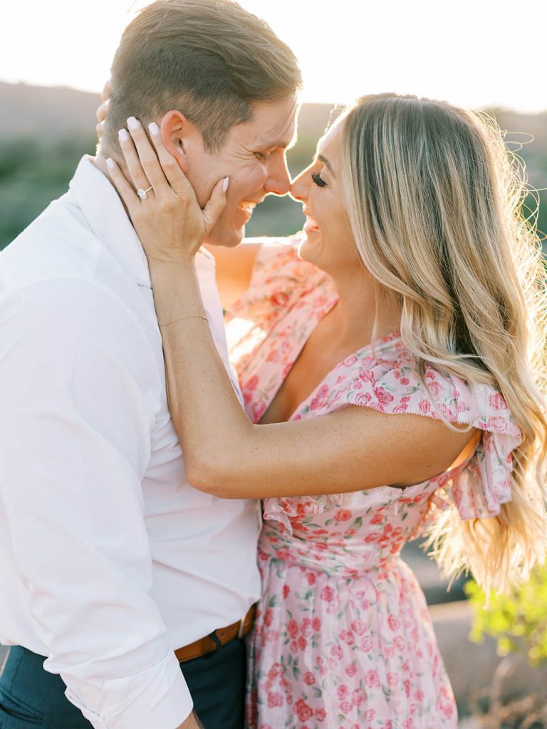 girl in pink dress kisses her fiance for engagement photo
