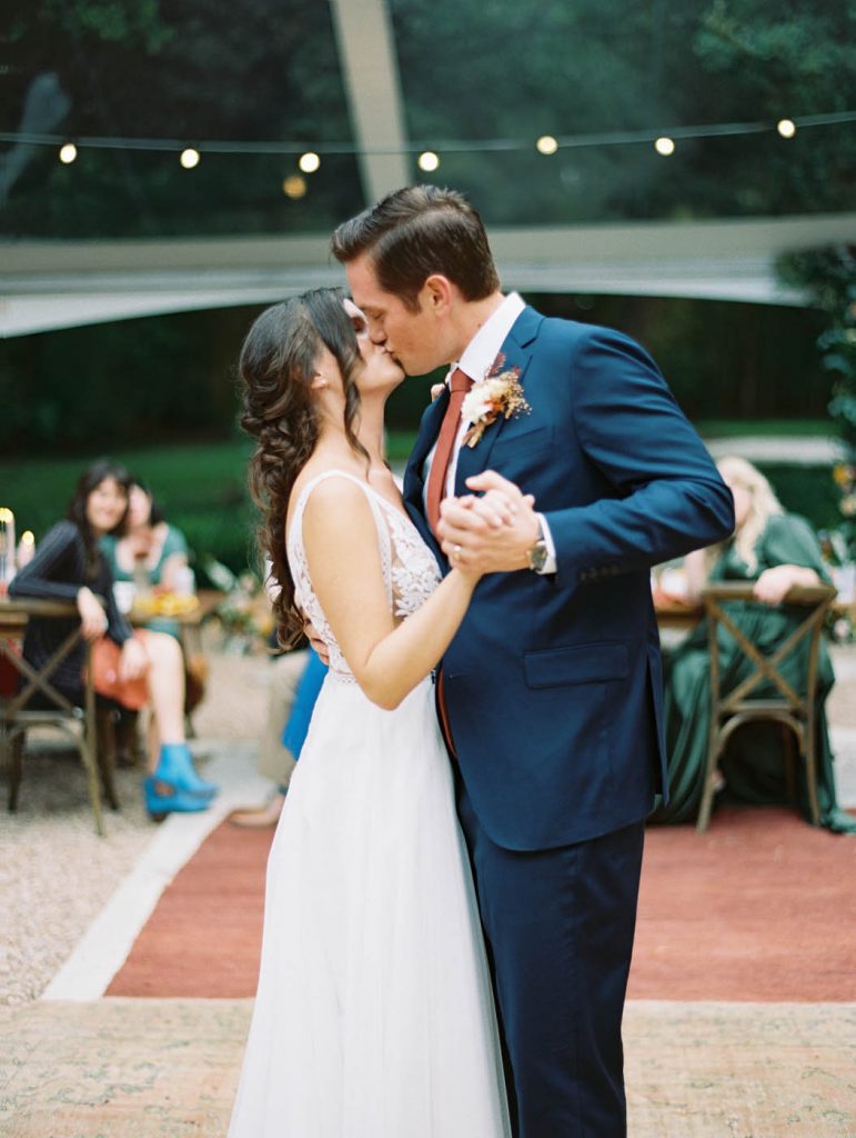 the couple kissing at the end of their first dance under a clear tent