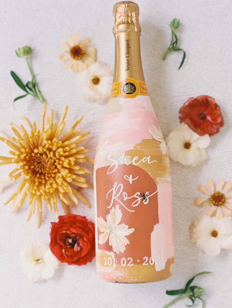 a custom champagne bottle painted by pens and needles co