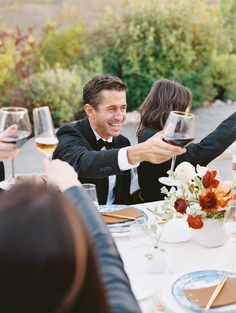 candid photo of a wedding guest toasting with wine