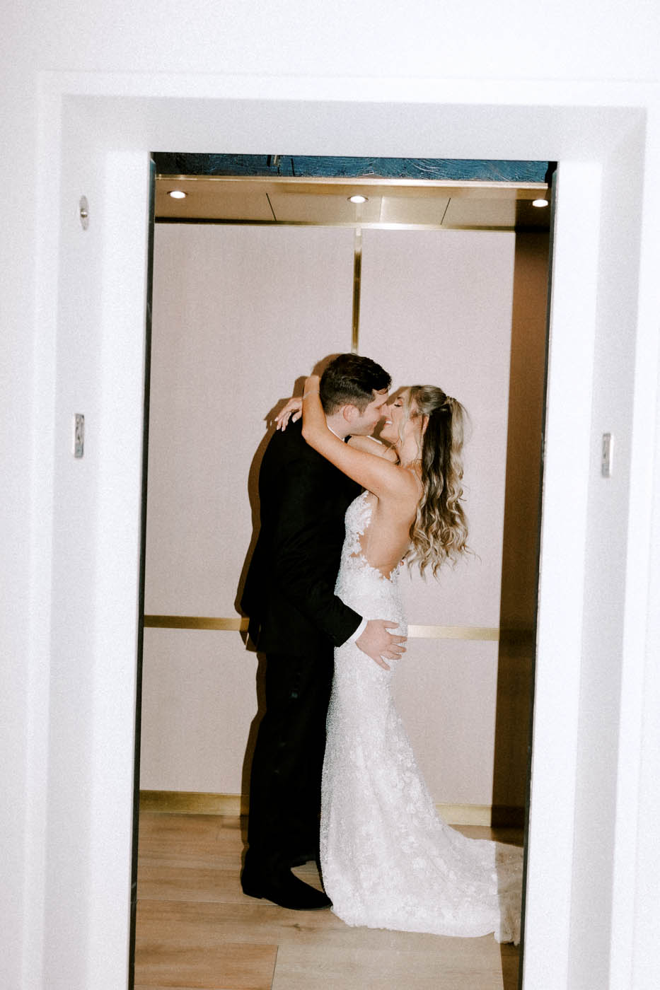 the bride and groom kiss in an elevator at the C Baldwin Hotel