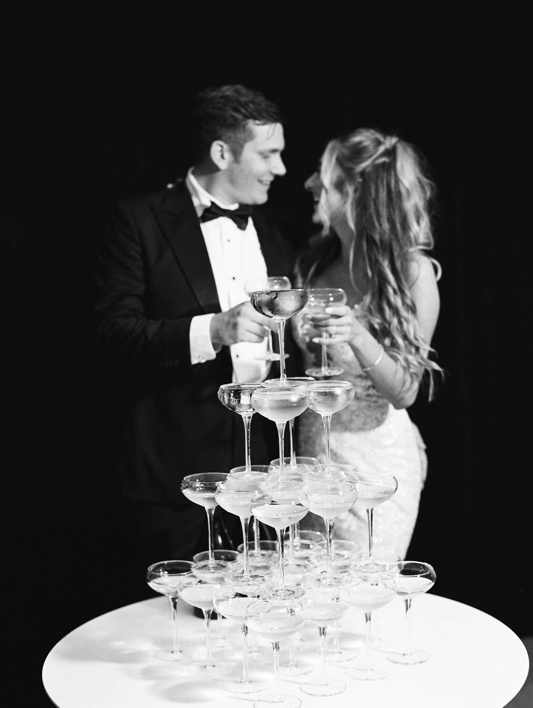 the bride and groom pose in front of their champagne tower