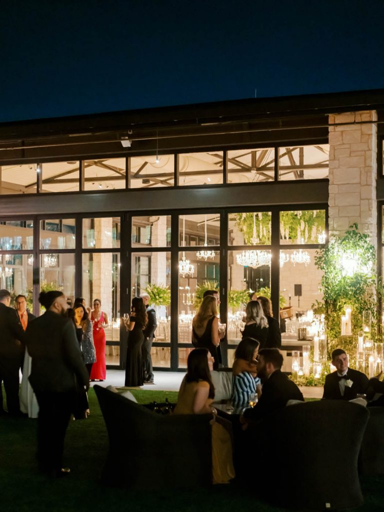 guests mingle together on the lawn with the reception ambience behind them