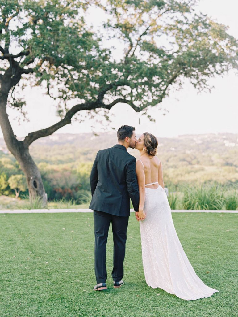 bride and groom kiss on the omni barton creek hill country lawn