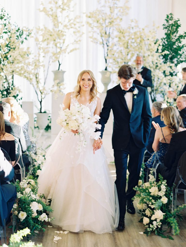 The bride and groom walk back down the aisle together smiling