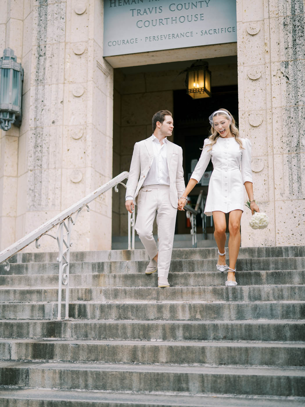 the couple who just eloped walks down the city hall stairs of the courthouse
