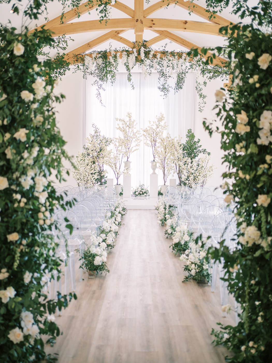 the epic ceremony decor with white indoor trees and bushels of greenery