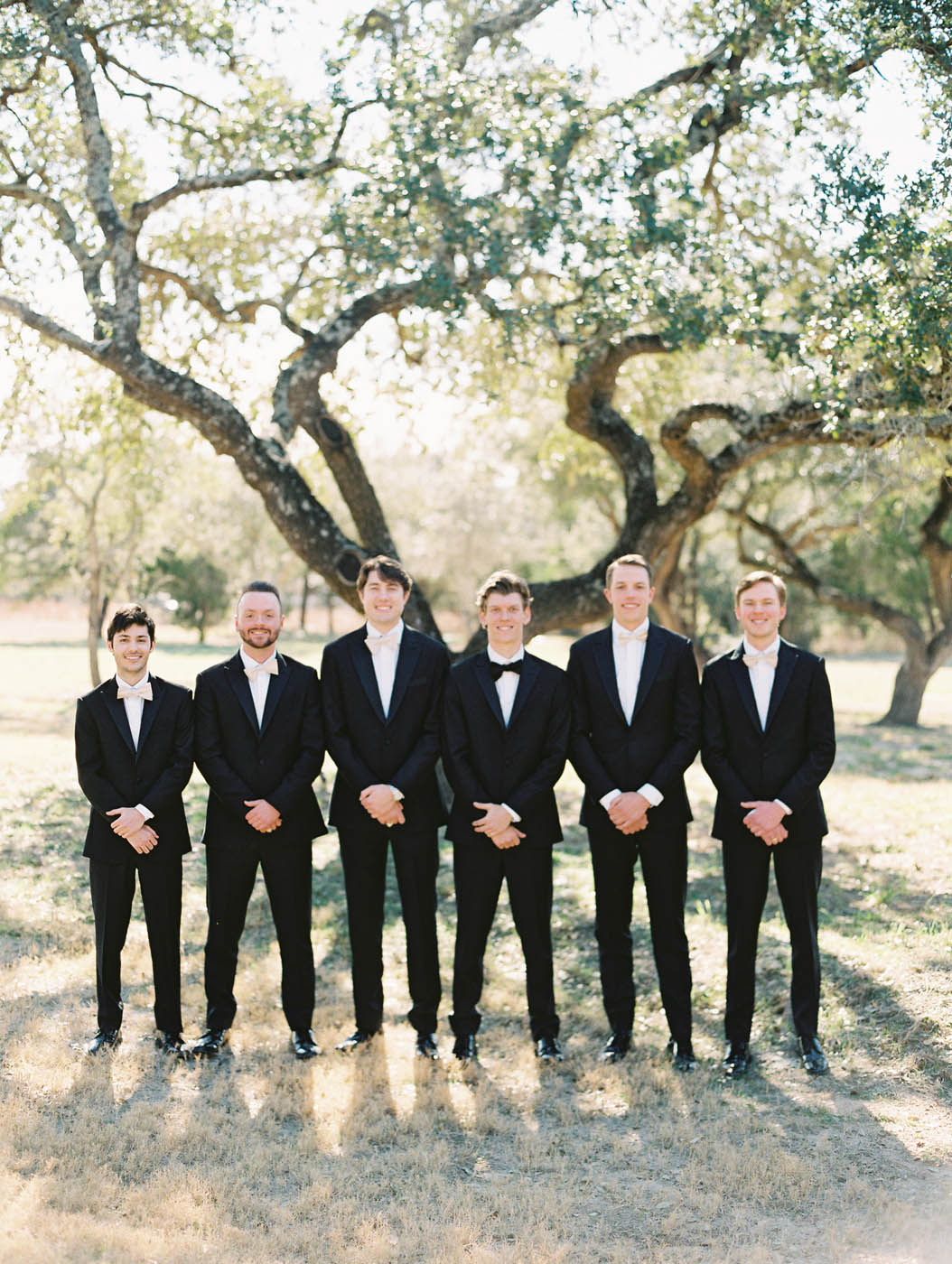 The groom and groomsmen group photo by the oak trees at The Arlo