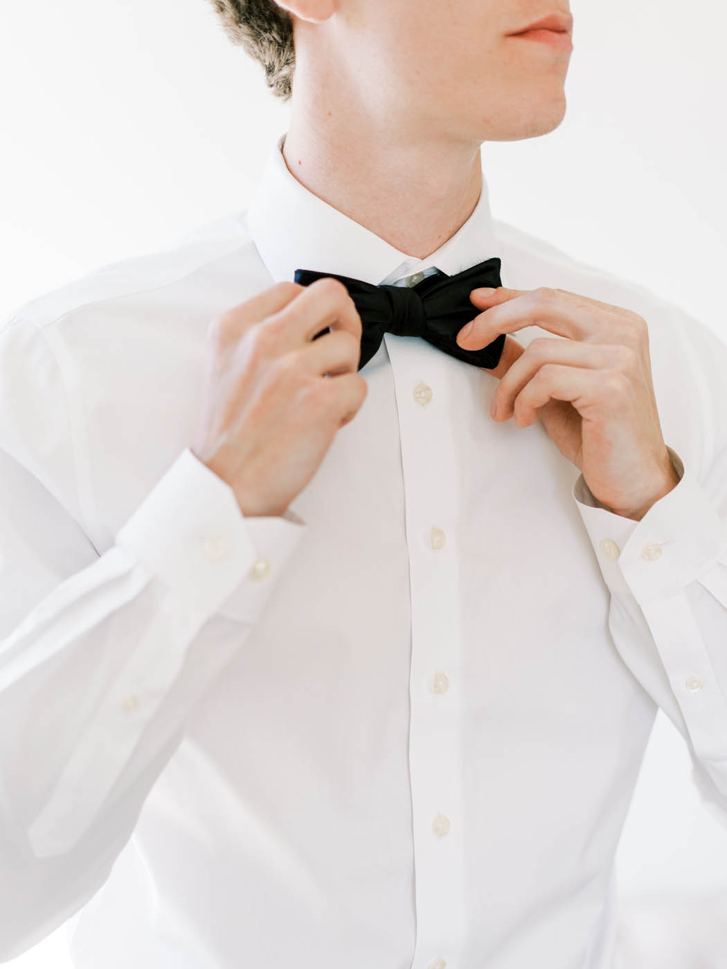 the groom tightens his tie as he gets ready to get married