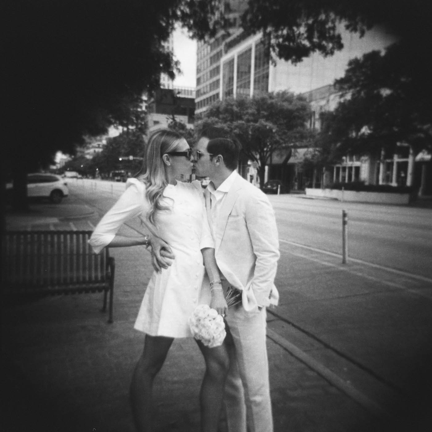 a holga film photo of a newly married couple kissing on the streets of downtown Austin