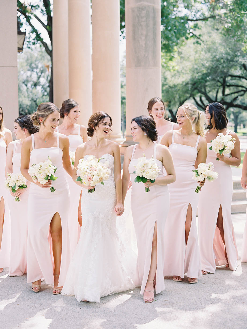 The bride walks with her bridesmaids who are wearing pink dresses