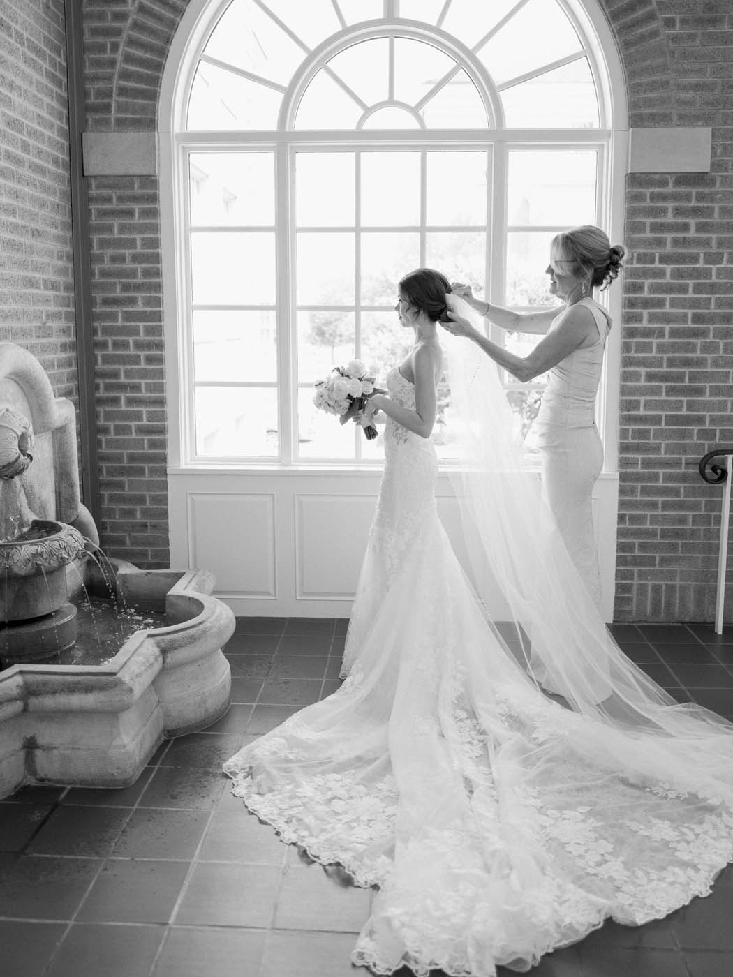 The bride gets her veil put on by her mother