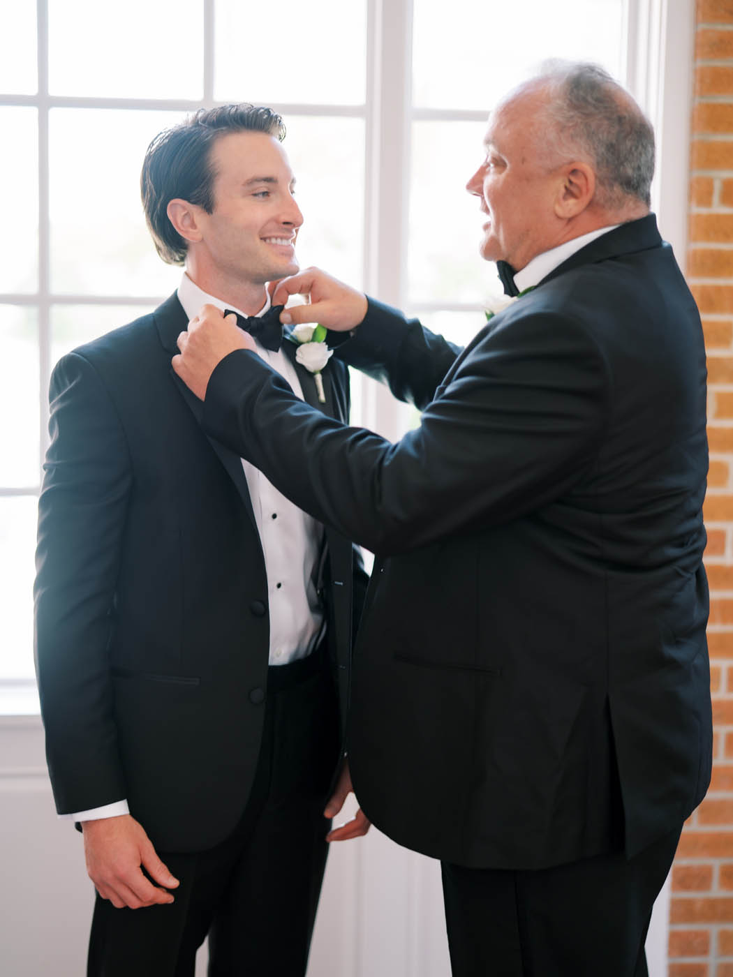 The groom is helped by his father as he ties his bowtie
