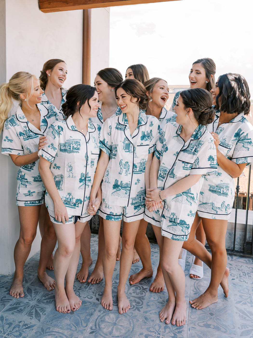 Bridesmaids pose for a photo in their pajamas on the balcony of Hotel Drover